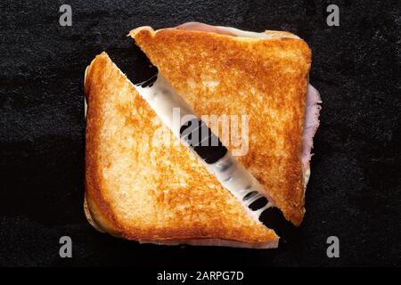 https://l450v.alamy.com/450v/2arpg7d/classic-cheese-and-ham-toasted-sandwich-cut-in-half-isolated-on-black-cast-iron-griddle-top-view-2arpg7d.jpg