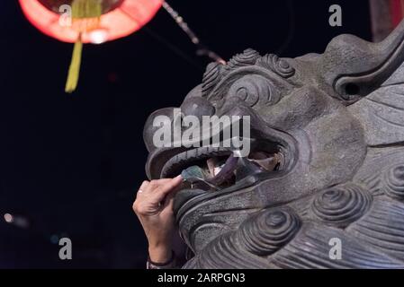 Capital Federal, Buenos Aires / Argentina; Jan 25, 2020: hand introducing money into the mouth of a chinese guardian lion statue, in the celebrations Stock Photo