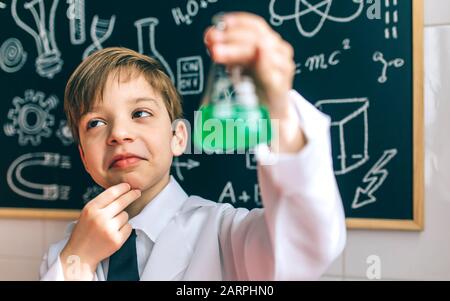 Thoughtful boy dressed as chemist with flask Stock Photo