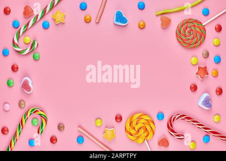 Sweet candy copy space frame with lollipops on pink background. Love to colorful sweetmeats in childhood concept Stock Photo