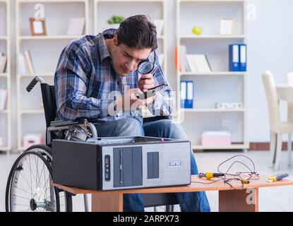 The computer repairman on wheelchair working Stock Photo