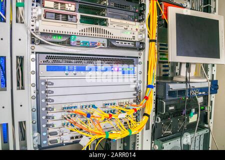 Rack with powerful Internet servers. The monitor is installed in a computer cabinet. A central router with multiple optical cables is located in the d Stock Photo