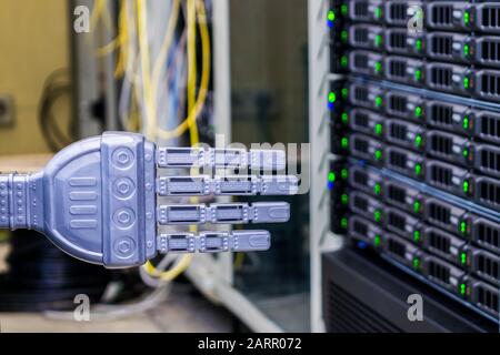 The robot's hand is in the server room of the data center. The concept of robotic control of computer systems. Stock Photo