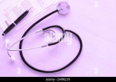 Stethoscope and medical documents on doctor table on purple background, close-up and view directly above. Medical examination, health care concept. Stock Photo