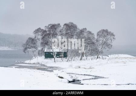 View of snow covered landscape of Loch Ossian and Loch Ossian Youth Hostel in Highland Region, Scotland, UK Stock Photo