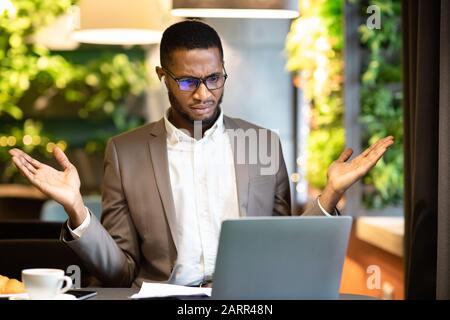 Surprised young afro manager looking at his computer Stock Photo