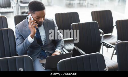 Concentrated afro businessman working on laptop in empty conference hall Stock Photo