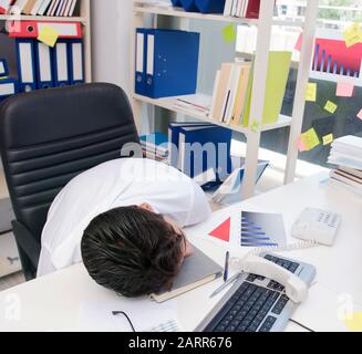 Businessman working in the office with piles of books and papers doing paperwork Stock Photo