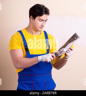 The young contractor employee applying plaster on wall Stock Photo