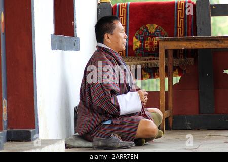 A Man in Traditional Bhutanese Clothes Sitting And Praying At A Temple in Bhutan Stock Photo