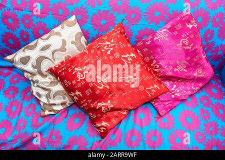 Ibajay, Aklan Province, Philippines: Three small size colorful pillows laying on a sofa, blue colored with pink floral patterns Stock Photo