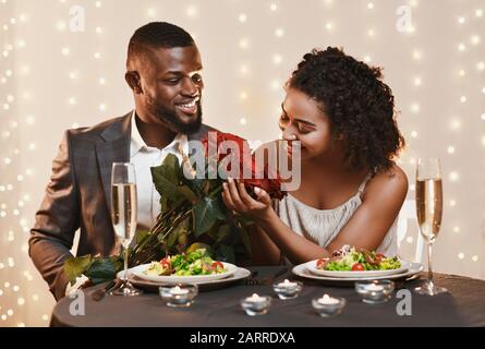 Handsome afro man giving beautiful flowers to his woman Stock Photo