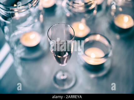 Red wine and tea light candles in glass jars. Stock Photo