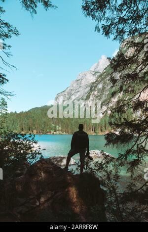 man climbing by rocks to shoot beautiful landscape of lake and mountains Stock Photo