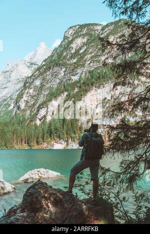 man climbing by rocks to shoot beautiful landscape of lake and mountains Stock Photo