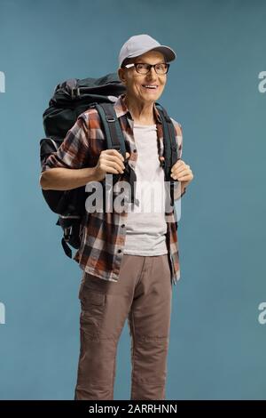 Elderly male hiker with a backpack over a blue background Stock Photo