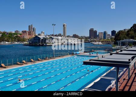 Sydney, NSW, Australia - October 31, 2017: Unidentified people in harborside swimming pool and yachts in Woolloomooloo Finger Wharf, Horizon apartments b Stock Photo