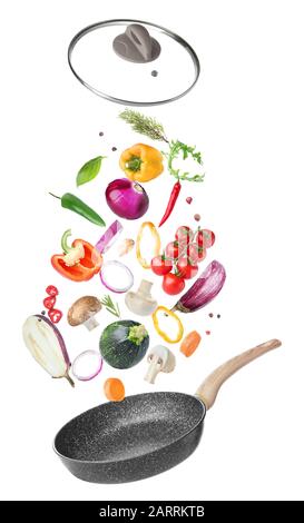 Frying pan and flying vegetables on white background Stock Photo