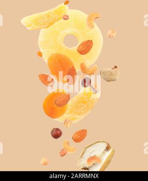 Different falling dried fruits and nuts on color background Stock Photo