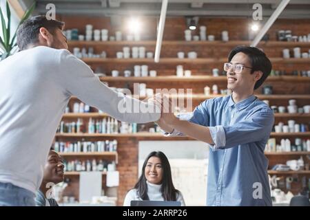 Two young male colleagues shaking hands, good job Stock Photo