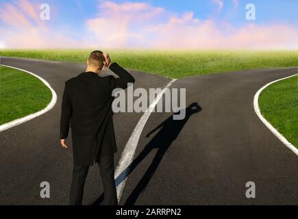 Confused businessman standing at crossroads. Concept of choice Stock Photo