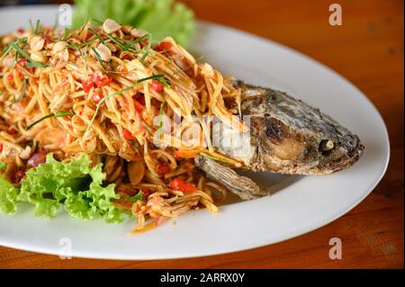 Fried Snakehead fish with spicy mixed herb on white plate Stock Photo