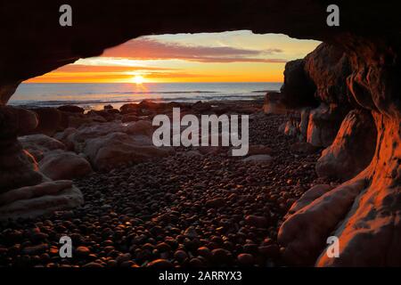 Sunrise over the Jurassic Coast seen from the sea cave near village of Beer, Devon Stock Photo