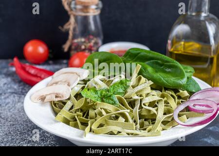 Pasta, vegetables, herbs and spices, olive oil, ingredients for Italian cuisine on a dark background. Copy space Stock Photo