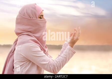 Beautiful Muslim woman praying outdoors Stock Photo