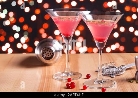 Martini glasses with cranberry cocktail and barmen tools on the wooden table. Stock Photo