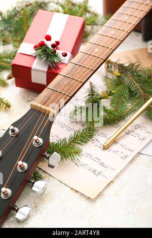 Guitar, note sheets, gift and Christmas decor on table Stock Photo