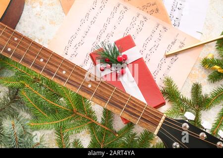 Guitar, note sheets, gift and Christmas decor on table Stock Photo