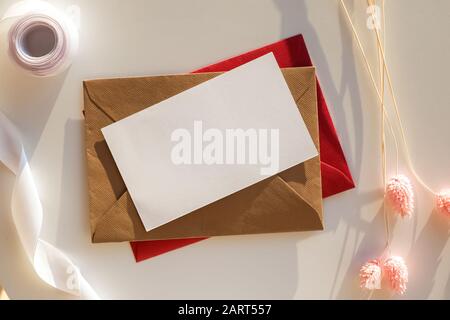 Empty paper card mock-up on the table with dry flowers and ribbon in natural sunlight Stock Photo