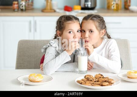 Portrait of cute twin girls drinking milk in kitchen Stock Photo