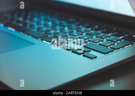 Close-up view of backlit laptop keyboard and blue light from the screen. Closed lid of a portable computer, concept of private information, not safe f Stock Photo