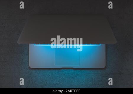 Top view of a laptop on a dark table, glowing blue screen. Minimalistic workplace, working with computer, using laptop at night and online privace con Stock Photo