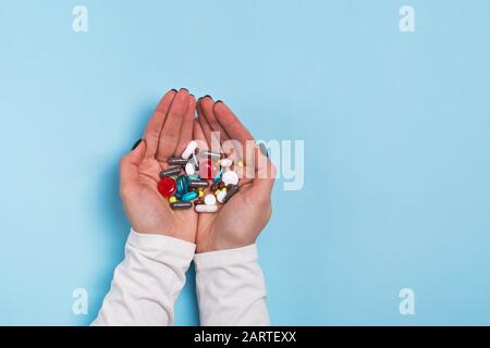 Woman's hands holding a different tablets and pills over blue Stock Photo