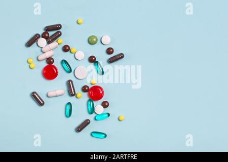 Different multi colored pills and tablets on blue background. Stock Photo