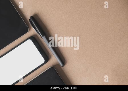 Business flat lay on brown paper background. Smartphone, tablet computer and notebook organizer on vintage background Stock Photo