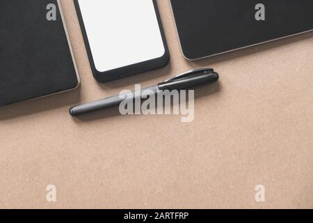 Business flat lay on brown paper background. Smartphone, tablet computer and notebook organizer on vintage background Stock Photo