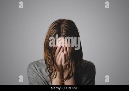 Woman covers face in hands. Concept of despair, depression, loss or mental condition Stock Photo