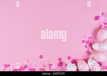 Easter flat lay with easter eggs and confetti in corner and empty copy space on pink background Stock Photo