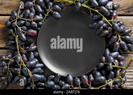 Plate with tasty sweet grapes on wooden table Stock Photo
