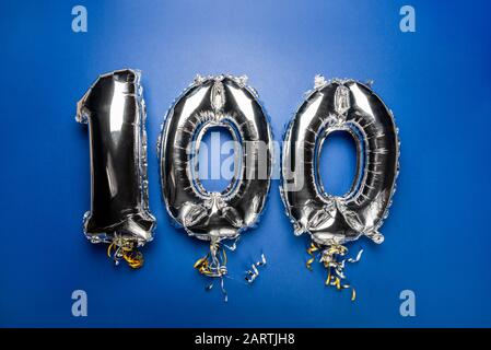 Balloon Bunting for celebration Happy 100th Anniversary made from Silver Number Balloons on blue background. Holiday Party Decoration or postcard conc Stock Photo