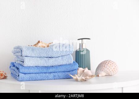 Stack of clean towels with soap and seashells on table Stock Photo