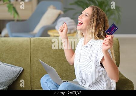 Happy young woman with credit card and laptop at home Stock Photo