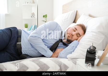 Tired businessman in formal clothes sleeping on bed Stock Photo