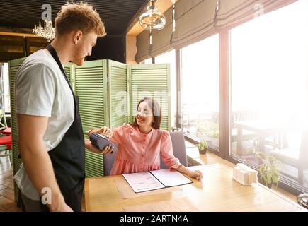 Woman paying bill in restaurant through terminal Stock Photo