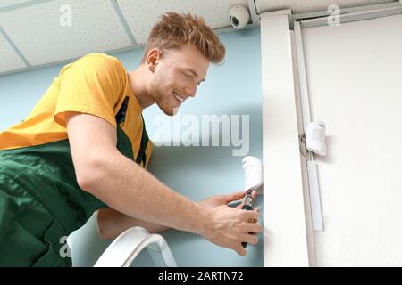 Electrician installing alarm system indoors Stock Photo