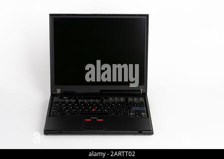 Old laptop on white background, which was produced in 2003, diagonal screen size 14 inches, outer cover reinforced titanium, metal hinges, red trackpo Stock Photo